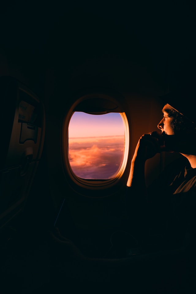 Ein Mann schaut aus dem Fenster eines Flugzeugs in den Sonnenuntergang: Sich sicher fühlen beim Fliegen